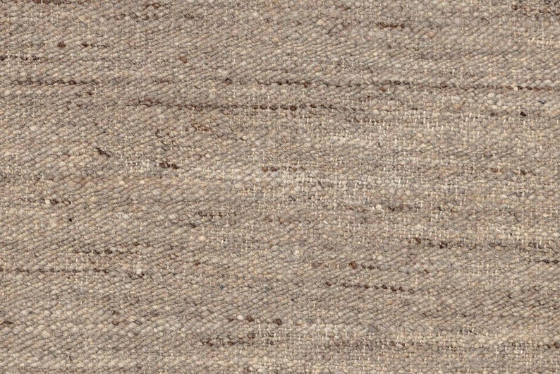 A very close-up, detailed view of the beige flatweave rug's texture, showing individual woven fibers.
