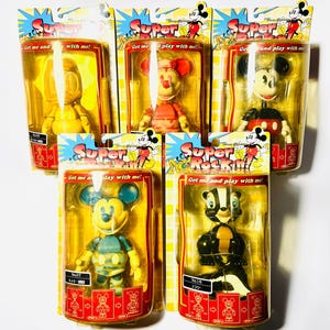 Peut inclure: Cinq figurines Disney Super Rockin' dans leur emballage blister d'origine. L'ensemble comprend un personnage jaune, Minnie Mouse, Mickey Mouse, un Mickey Mouse camouflage et le personnage Flower. Chaque emballage porte le texte Get me and play with me.