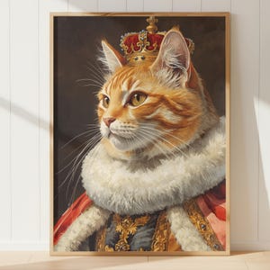 Op de afbeelding: Een ingelijst portret van een oranje tabby kat met een rode en gouden kroon en koninklijke kleding. De kat heeft een witte bontkraag en staat tegen een donkere achtergrond. Het kunstwerk is een koninklijke afbeelding van een kat.