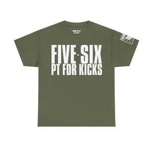 Pode incluir: Camiseta verde-oliva com o texto branco "FIVE SIX PT FOR KICKS". A camiseta também apresenta um pequeno gráfico na manga e um pequeno logotipo na gola. É uma peça de roupa casual.