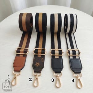 Puede incluir: Cuatro correas de bolso a rayas en varias combinaciones de colores: marrón y beige, negro y dorado, negro y beige y negro y blanco. Cada correa tiene herrajes dorados y un extremo de cuero o polipiel con un cierre.