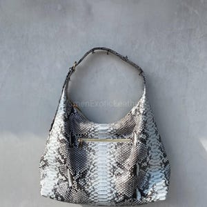 May include: A set of three ceramic mugs with a speckled, matte finish. The mugs are in shades of cream, light grey, and dark grey. Each mug has a simple, minimalist design and a rounded handle.