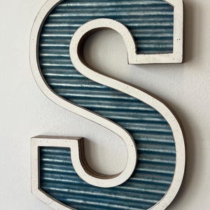 May include: A handmade wooden sign with the text "Welcome to our home" in a handwritten style. The sign is painted white with a dark stained frame. A small, decorative heart is attached to the bottom.