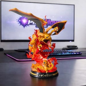 May include: A detailed figurine of a Charizard, a popular character from the Pokémon franchise. The figurine is orange and yellow with red flames, and the word "Evolution" is written on the base. The figurine is on a desk with a computer monitor in the background.