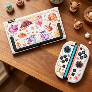 May include: White Nintendo Switch console and controllers with a colorful cartoon design featuring various characters. The design includes floral accents and a variety of colors, including pink, orange, blue, and purple. The controllers have blue and orange accents.