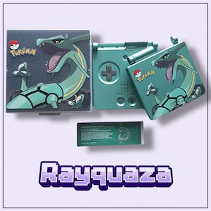 Peut inclure: Une console Game Boy Advance SP de couleur sarcelle avec un étui et une cartouche de jeu assortis. L'étui et la console présentent un design Rayquaza avec le logo Pokémon. Le mot "Rayquaza" est affiché en violet.