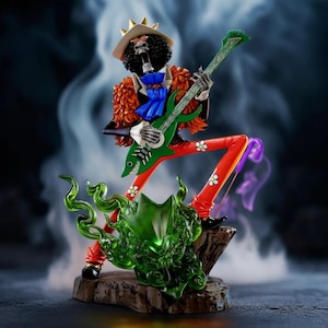 Puede incluir: Figura de un personaje esqueleto tocando una guitarra verde. El personaje lleva una corona, sombrero y chaqueta naranja. Pantalones rojos con detalles de flores blancas y zapatos negros completan el look. Energía verde arremolinándose alrededor de la base.