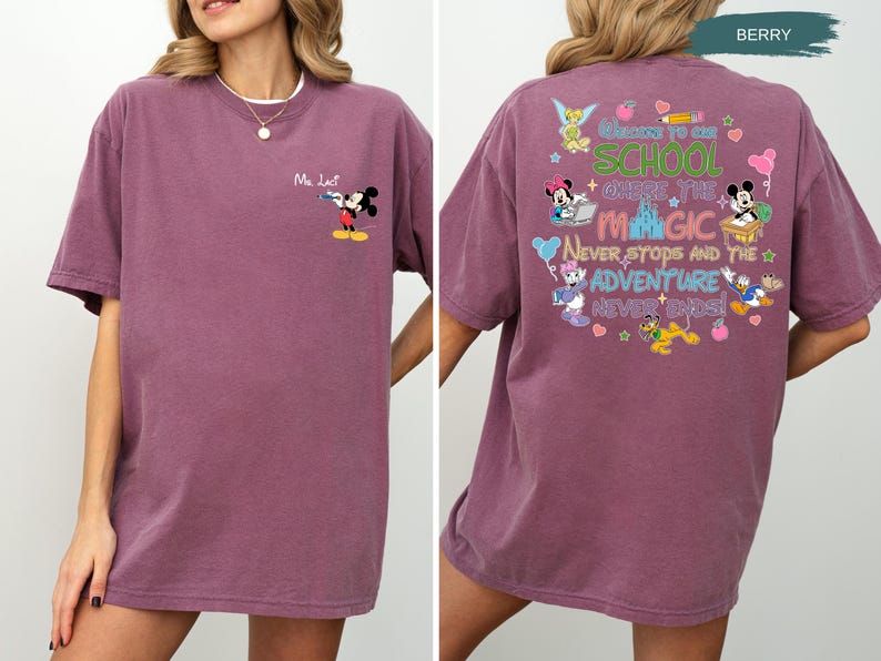 May include: Berry-colored t-shirt featuring Mickey Mouse on the front and a colorful graphic on the back. The back graphic includes the text "Welcome to our school where the magic never stops and the adventure never ends!" with various Disney characters.