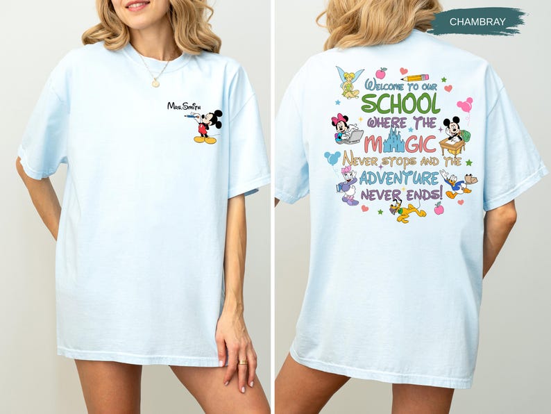 May include: Light blue t-shirt with a cartoon graphic of Mickey Mouse and the text "Mrs. Smith" on the front. The back of the shirt features a colorful design with the text "Welcome to our school where the magic never stops and the adventure never ends!"