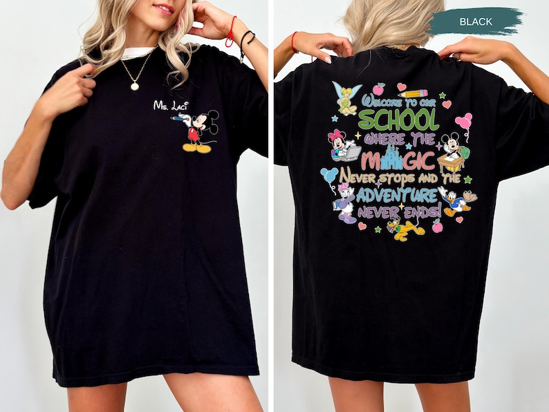 May include: Black t-shirt featuring Mickey Mouse on the front and a colorful graphic on the back that reads "Welcome to our school where the magic never stops and the adventure never ends." The shirt has a white collar.