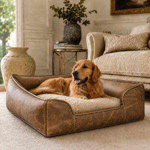 May include: A rectangular pet bed featuring a distressed brown leather-effect exterior with visible stitching and a plush, cream-coloured faux fur interior cushion. A golden-coloured dog is lying comfortably inside the bed on the soft surface.