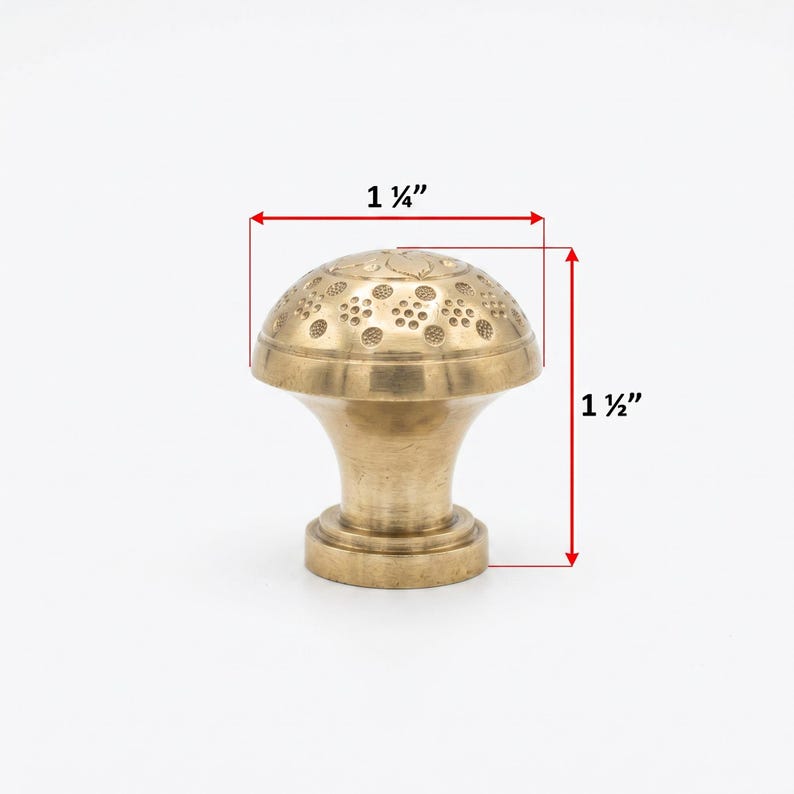 Puede incluir: Un tirador de armario de lat&oacute;n con un dise&ntilde;o floral decorativo en la parte superior. El tirador mide 3,18 cm de ancho y 3,81 cm de alto. El tirador tiene un dise&ntilde;o cl&aacute;sico y vintage.