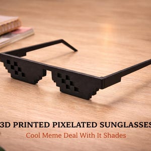 May include: Black 3D printed pixelated sunglasses with a meme design. The sunglasses have a square pixelated design on the lenses and are resting on a wooden surface. Text on the image reads: 3D Printed Pixelated Sunglasses, Cool Meme Deal With It Shades.