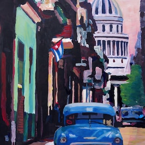 May include: A blue vintage car parked on a street in a city with a large building in the background. The building has a dome and columns. A Cuban flag is hanging from a building on the left side of the image.