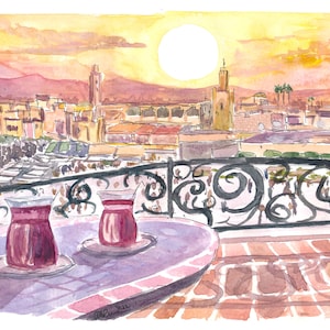 May include: Two glasses of red tea on a table with a view of a city skyline at sunset. The city is in the background and the glasses are in the foreground. The sun is setting behind the city and the sky is a mix of orange, yellow, and pink.