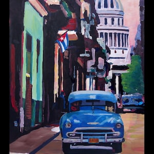 May include: A blue vintage car drives down a narrow street in Havana, Cuba. The car is in focus, while the buildings and the sky are blurred in the background. A Cuban flag hangs from a building.