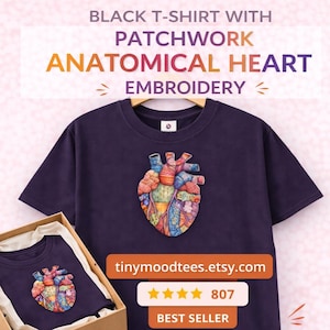 Puede incluir: Una camiseta negra con un diseño de bordado de corazón anatómico de patchwork colorido. La camiseta se muestra en una percha de madera y en una caja. El texto de la imagen dice "Black T-Shirt with Patchwork Anatomical Heart Embroidery."