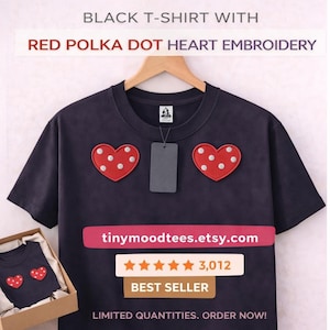 May include: A black t-shirt featuring red polka dot heart embroidery. The shirt is hanging on a wooden hanger. The image includes the text "BLACK T-SHIRT WITH RED POLKA DOT HEART EMBROIDERY" and the Etsy shop name "tinymoodtees.etsy.com".
