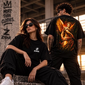 Może przedstawiać: Czarny t-shirt z małym białym logo ZYAR na piersi oraz dużą, szczegółową grafiką na plecach przedstawiającą złotą skrzydlatą postać w klasycznym stylu na ognistym, ciemnym tle. Koszulka jest zestawiona z czarnymi spodniami typu cargo.