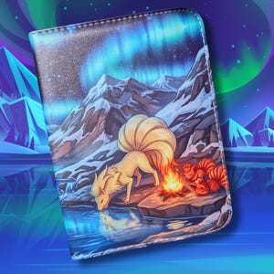 May include: A wallet featuring a fantasy illustration of a fox-like creature drinking from a lake, with a campfire and two other creatures nearby. The background shows snow-capped mountains and an aurora borealis.