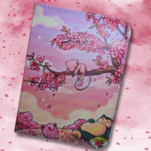 Può includere: Un portafoglio rosa e viola con un'illustrazione a cartoni animati di una creatura addormentata su un ramo con fiori rosa. Un'altra creatura dorme sotto. Lo sfondo è un cielo rosa e viola.
