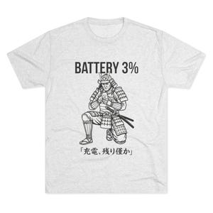 Peut inclure: T-shirt gris clair avec une illustration en noir et blanc d'un guerrier samouraï agenouillé, regardant un téléphone. Le texte "BATTERY 3%" est au-dessus de l'illustration, et du texte japonais est en dessous.