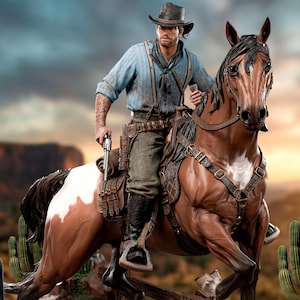 May include: A detailed figurine of a cowboy riding a brown and white horse. The cowboy wears a blue shirt, hat, and holds a gun. The horse is saddled and stands near a "Wanted" poster and cacti.