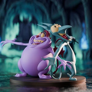 May include: A figurine set featuring two cartoon characters from the movie Hercules. One is a large, purple creature with a wide grin, and the other is a blue, winged creature with a red chest. They are posed on a brown circular base.