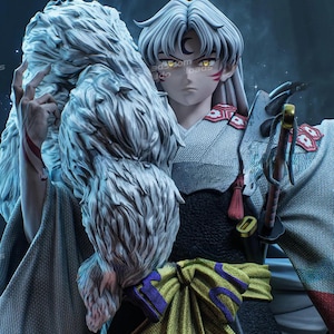 Puede incluir: Figura detallada de un personaje con cabello blanco, ojos amarillos y marcas rojas. La figura viste un atuendo negro y gris con una faja verde y morada y lleva una espada. Un objeto blanco grande y esponjoso se sostiene sobre el hombro de la figura.