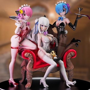 May include: A detailed figurine set featuring three anime-style figures in maid outfits. The figures are posed on a red ornate chair, each holding a tray. The figures have pink, white, and blue hair, and wear black and red lingerie-style outfits.