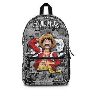 May include: A backpack featuring a black and white manga panel print from One Piece. The front displays a colorful illustration of Monkey D. Luffy wearing a straw hat and red shirt, with the text ONE PIECE and a skull logo at the top.