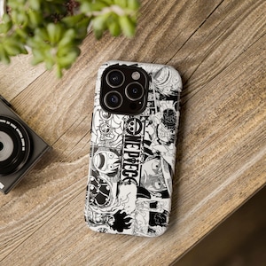 Könnte beinhalten: Eine Smartphone-Hülle mit einer schwarz-weißen Manga-Collage von One Piece-Charakteren und dem One Piece-Logo. Das Design bedeckt die gesamte Rückseite des Telefons, einschließlich des Bereichs um die dreifache Kameralinse oben links.