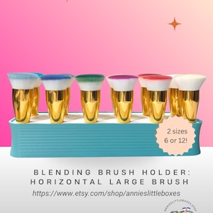 May include: A white ceramic mug with a black handle and the text "But First, Coffee" in a bold, black font. The mug is set against a blurred background, suggesting a cozy setting.