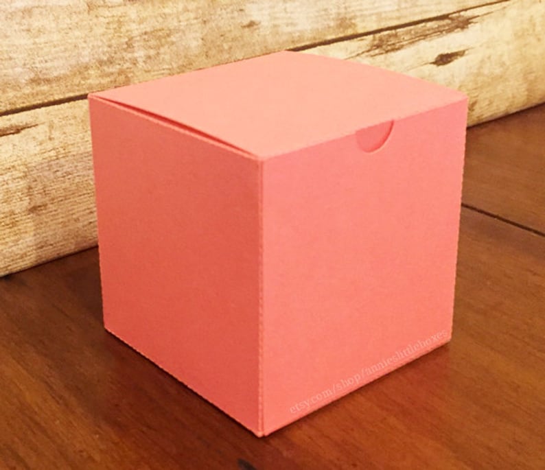 May include: A coral pink square gift box with a fold-over top. The box is sitting on a wooden surface. etsy.com/shop/annieslittleboxes