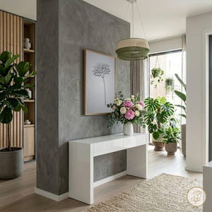 Puede incluir: Un interior moderno con una consola blanca, una impresión floral enmarcada y un jarrón con flores. La habitación tiene una pared de acento gris, elementos de madera y plantas en macetas. Una lámpara colgante verde y beige cuelga del techo.