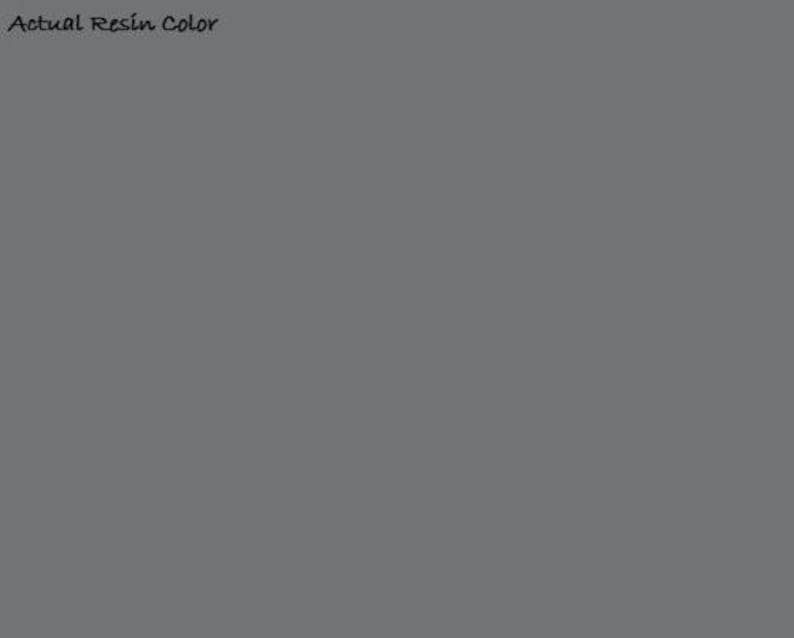 May include: A solid, flat, medium-gray square field representing the actual resin color. The text 'Actual Resin Color' is printed in black in the upper left corner of the image. The surface is uniform in tone and texture throughout the entire area.