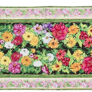 May include: A floral table runner with a central panel of colorful flowers, including red, yellow, and purple blooms, set against a dark background. The runner has a green border and is framed by a light pink floral pattern.