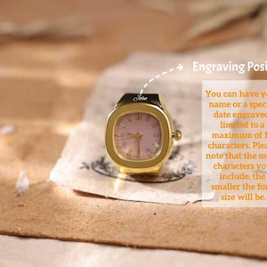 May include: A gold-toned watch with a square face and a pink dial. The watch has the name "John" engraved on it. The image also includes text that says "Engraving Position" and details about engraving.