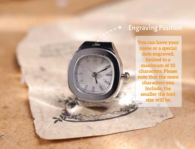 Puede incluir: Un reloj de anillo plateado con una esfera rectangular y una esfera de color claro. El reloj tiene una peque&ntilde;a corona y la palabra "John" est&aacute; grabada en la parte superior. La imagen incluye texto sobre grabar un nombre o fecha.