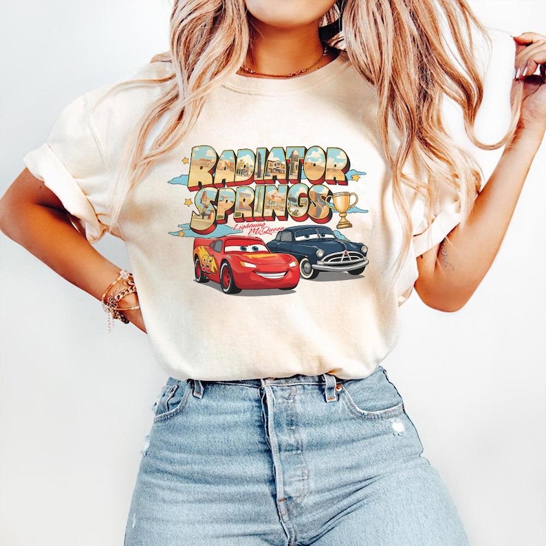 May include: A white ceramic mug with a black handle and the text "But First, Coffee" in a black, bold font. The mug is on a wooden surface.