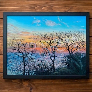 May include: A framed landscape painting featuring a vibrant sunset over a body of water. Silhouetted trees and stylized bubbles are in the foreground. The sky transitions from blue to orange and yellow, with wispy clouds.
