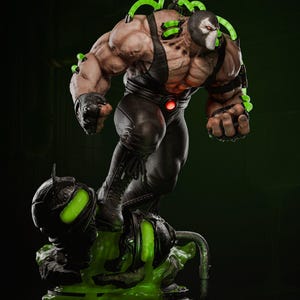 Op de afbeelding: Een gedetailleerd beeld van de DC Comics-schurk Bane, dynamisch geposeerd. De figuur is gespierd, gekleed in een zwarte outfit met een masker en buizen. Groene gloeiende elementen en een basis met groene vloeistof dragen bij aan het dramatische effect. Het beeld is ongeveer 30 cm hoog.