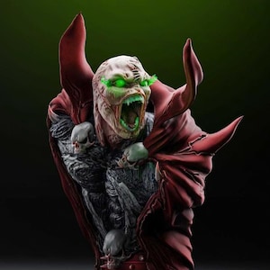 Può includere: Busto dettagliato di una figura mostruosa con occhi e bocca verde brillante e un mantello rosso. La figura ha un volto pallido e strutturato con la bocca aperta, che rivela denti affilati. Il busto presenta dettagli di teschio e un'estetica oscura e minacciosa.