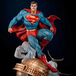 May include: A detailed statue of Superman in a dynamic pose, wearing his iconic blue suit with the red "S" emblem, red trunks, and cape. The figure is posed atop a golden globe with "DAILY PLANET" inscribed. The statue is set against a dark background.