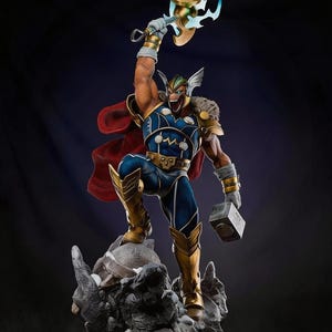Op de afbeelding: Een gedetailleerd beeld van Thor, de Marvel Comics-superheld, in een dynamische pose. Hij draagt een blauw en goud kostuum, een rode cape en houdt een gouden hamer met blauwe bliksem vast. Het beeld staat op een rotsachtige basis.