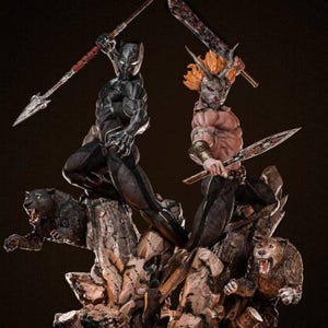Könnte beinhalten: Detaillierte Statue mit zwei Figuren in dynamischen Posen. Eine Figur trägt einen schwarzen Anzug mit einem Speer, die andere mit orangefarbenem Haar und einer Maske, die ein Schwert schwingt. Der Sockel zeigt knurrende Bärenfiguren und felsiges Gelände.