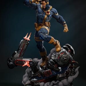 Op de afbeelding: Gedetailleerd beeld van een superheld in een dynamische pose, gekleed in een blauw en geel kostuum met een rood embleem. De figuur staat op een mechanische basis met rook- en vuureffecten, met ingewikkelde details en texturen.