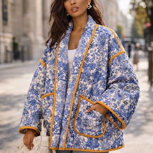 May include: A blue and white floral print jacket with orange trim. The jacket has a relaxed fit, pockets, and a shawl collar. The jacket is worn with blue jeans and a white handbag. The jacket is a stylish outerwear option.