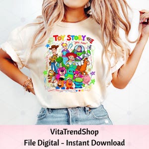 Peut inclure: Un t-shirt couleur cr&egrave;me avec une impression graphique color&eacute;e des personnages de Toy Story, dont Woody, Buzz l'&Eacute;clair et Jessie. Le texte "TOY STORY" et "yee haw" figure au-dessus des personnages, entour&eacute; de dessins au trait griffonn&eacute;s.