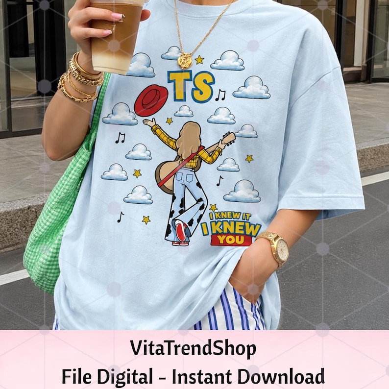 K&ouml;nnte beinhalten: Ein hellblaues T-Shirt mit einer grafischen Illustration einer Person mit langem Haar, die eine Akustikgitarre spielt und ein gelbes Karohemd sowie eine Hose mit Kuhfleckenmuster tr&auml;gt. Das Design zeigt Wolken, Sterne, Noten, einen roten Hut und den Text TS I KNEW IT I KNEW YOU.
